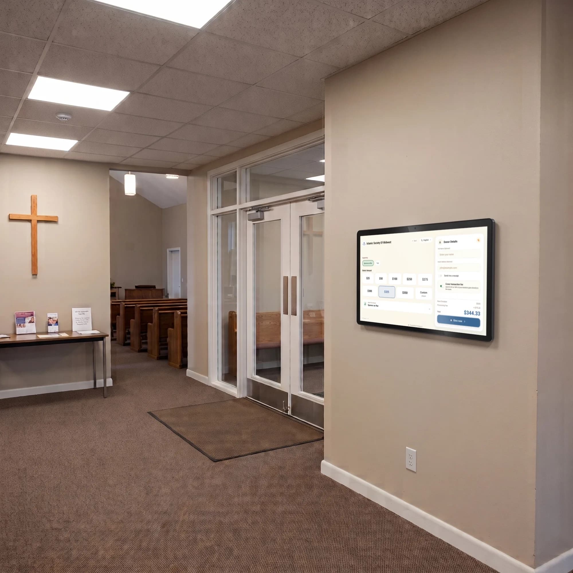 Wall-mounted Givebear donation kiosk in a church lobby outside the sanctuary