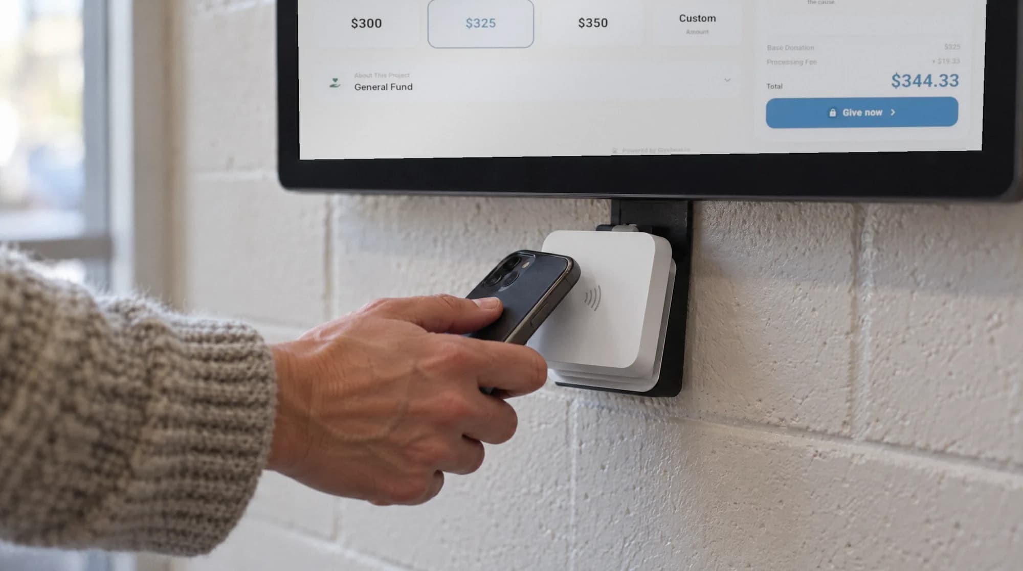 Close-up of a phone tapped on the card reader under a kiosk screen
